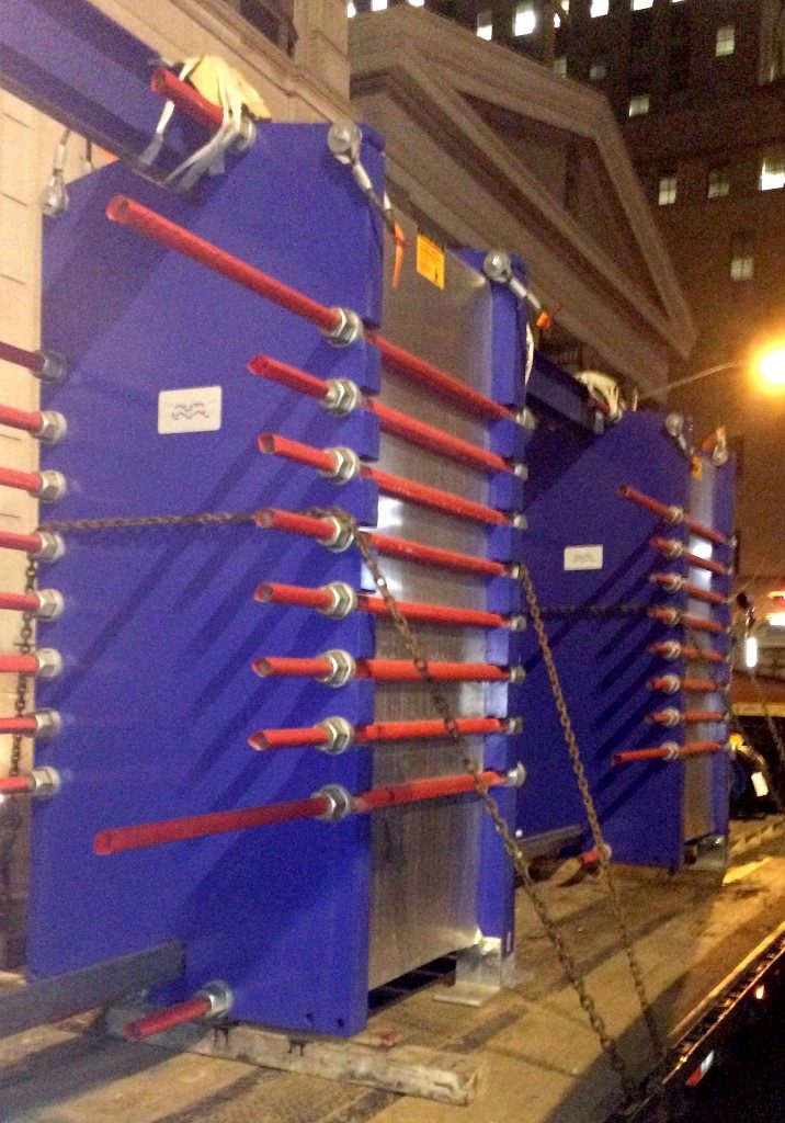 Blue and red cooling tower chained to flatbed of truck