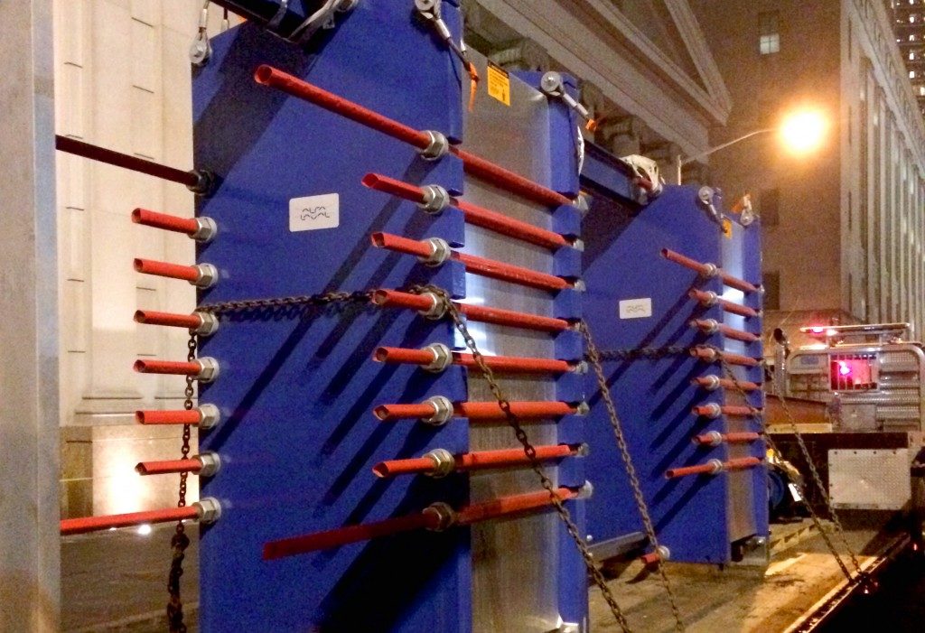 Blue and red cooling tower chained to flatbed of truck