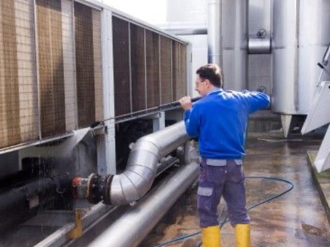 a man pressure washing outside of industrial hvac system